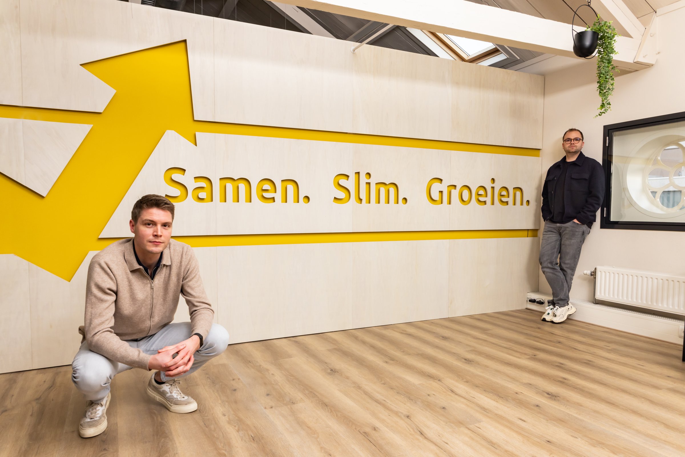 Nick en Olav bij de wand Samen. Slim. Groeien. op het kantoor van Succesfactor